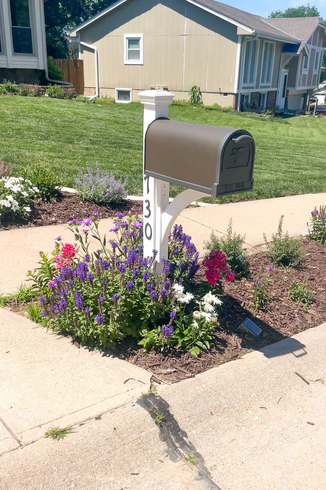 Beautiful, white mailbox surrounded by flowers.